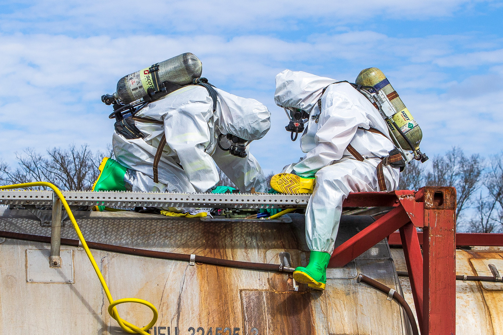 Hazardous materials response technicians working on a tank container